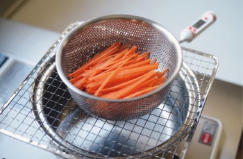 ❷鍋に８分目程度まで水を入れて湯を沸かします。一度火を止め、鍋の上に網をのせ（キッチン温度計は鍋と網の間に挟む）、素材を入れたザルを網の上にのせます