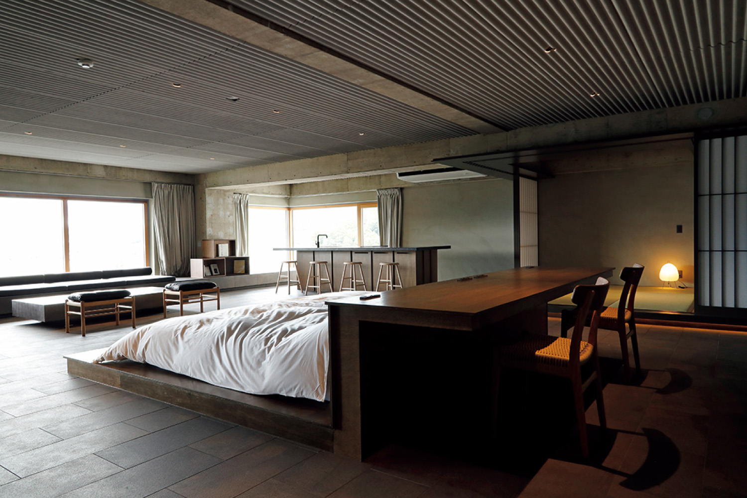 全室かけ流しの温泉付きブックホテル「松本本箱」の客室はコンクリート壁を生かし、天然木の家具を配したスタイリッシュなデザイン。