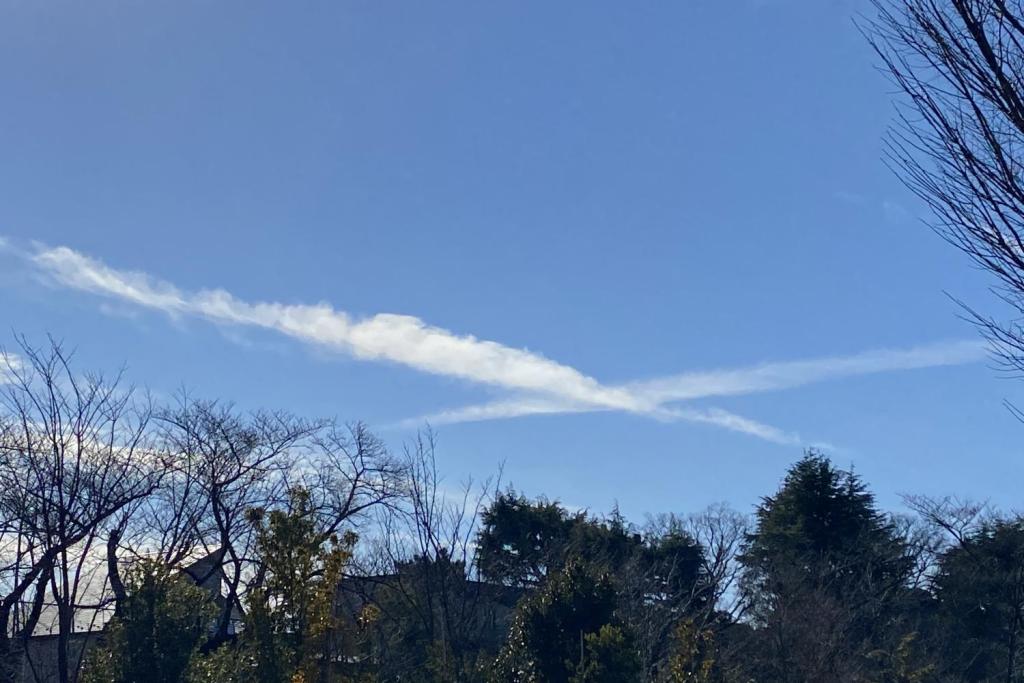 クロスしてぶつかりそうな2本の飛行機雲